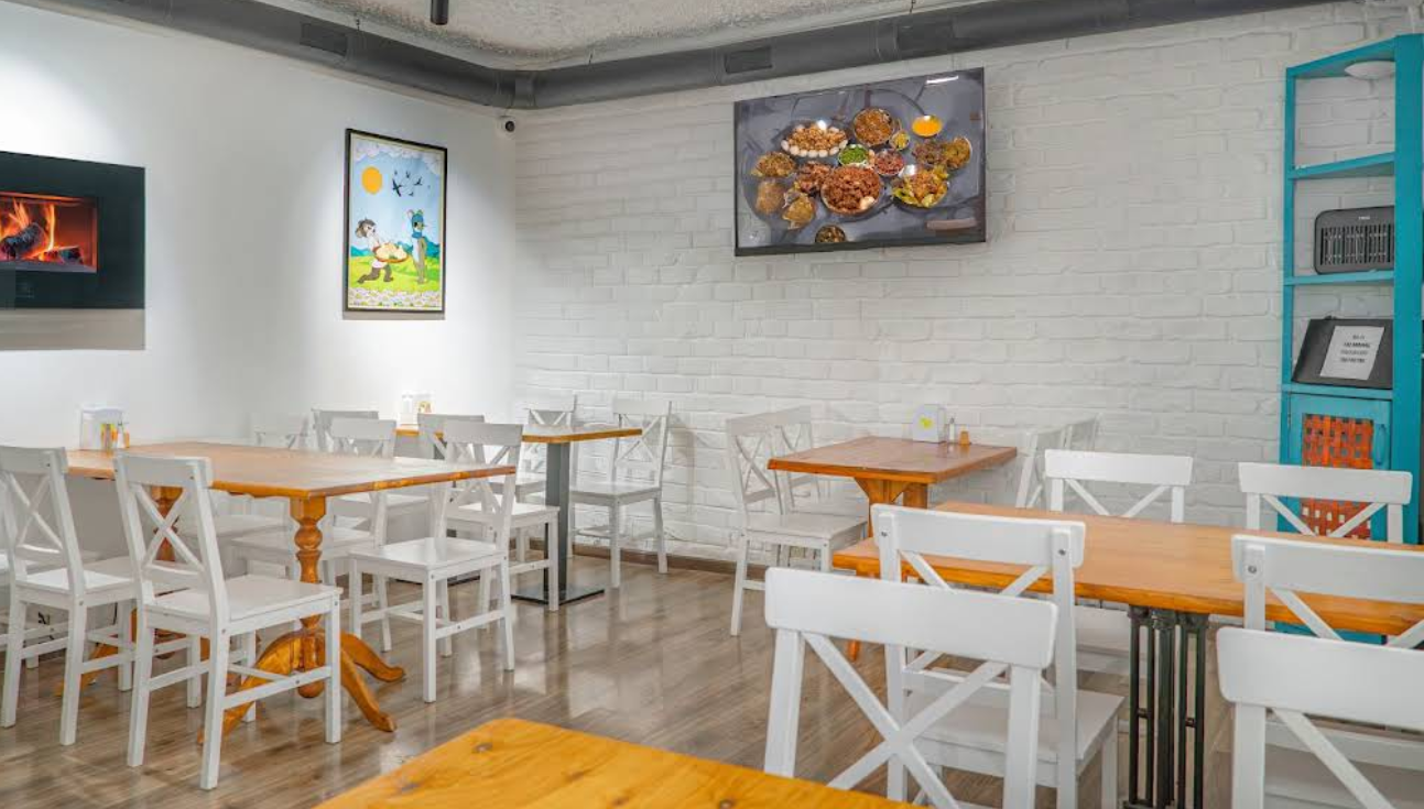 Interior Dining Space - Clean and modern Restaurant in Tbilisi with white furniture and Indian food display on TV